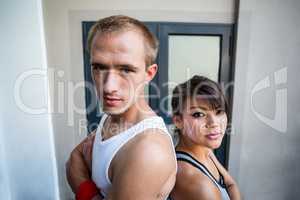 Portrait of extreme athletes standing back to back with arms cro