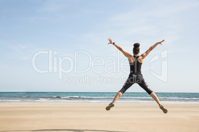 Fit woman leaping on the sand