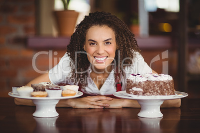 Waitress bending over chocolate cake and cupcakes
