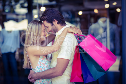 Smiling couple with shopping bags hugging closely