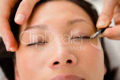 Woman placing fake eyelash on a patient