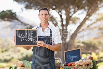 Smiling farmer holding a locally grown sign