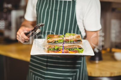 Waiter holding a plate of sandwiches