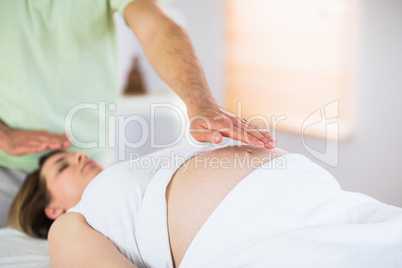 Relaxed pregnant woman getting reiki treatment