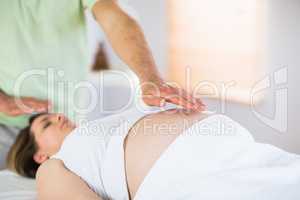 Relaxed pregnant woman getting reiki treatment