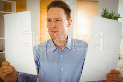 Serious businessman holding two paper sheets