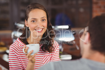 Smiling young woman enjoying coffee with her friend