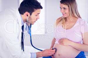 Doctor talking to smiling pregnant patient while examining her s