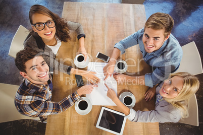 Smiling friends drinking coffee and pointing on paper
