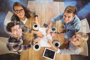 Smiling friends drinking coffee and pointing on paper