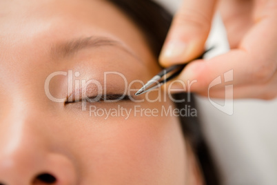 Woman placing fake eyelash on a patient