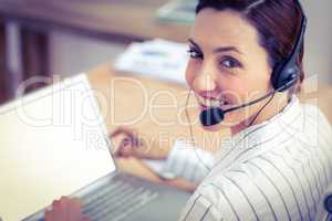 Portrait brunette businesswoman smiling using laptop and headpho