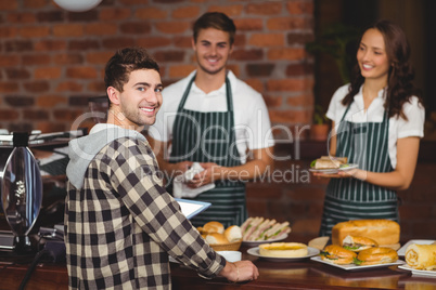Smiling waiters and customer looking at the camera