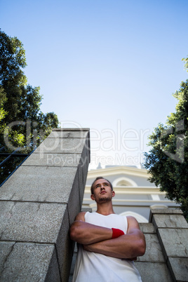 Extreme athlete standing next to wall with arms crossed