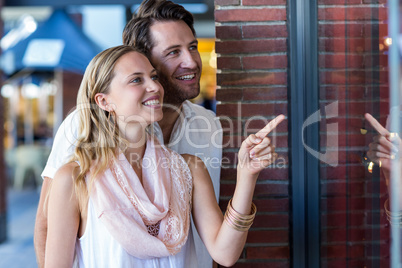 Smiling couple going window shopping and pointing at window