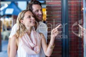 Smiling couple going window shopping and pointing at window