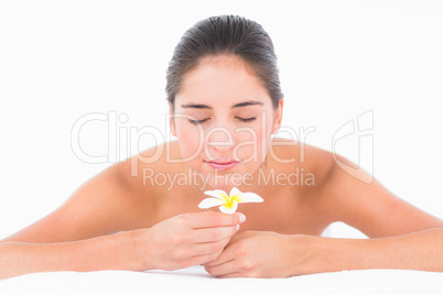 A portrait smiling pretty brunette on massage table with flowers