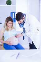 Doctor examining stomach of pregnant patient