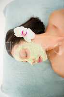 Attractive having green cream on her face at spa center