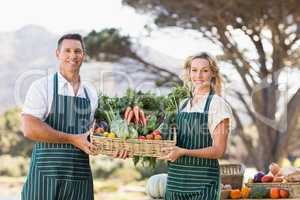 Smiling farmer couple holding a vegetable basket