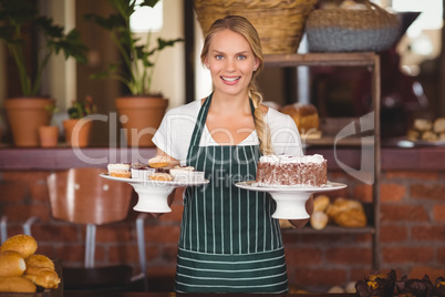 Pretty waitress holding a chocolate cake and cupcakes