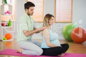 Masseur massaging shoulders of pregnant woman