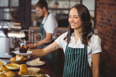 Smiling waitress serving a muffin