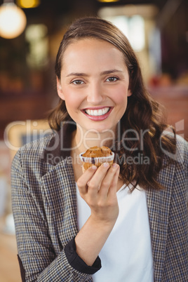 Smiling young woman showing muffin