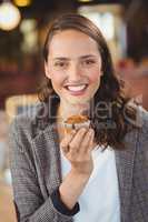 Smiling young woman showing muffin