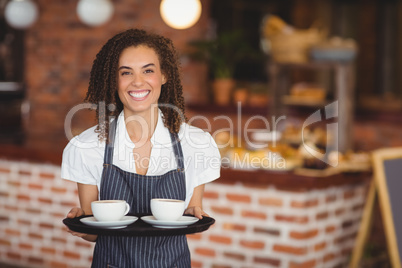 Smiling barista holding a tray of coffee cups