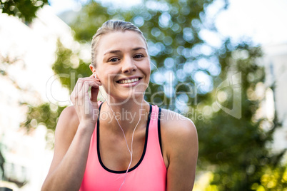 Portrait of a beautiful athlete putting her headphones