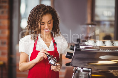 A smiling barista pressing coffee