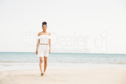 Stylish woman walking on the sand