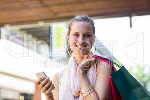 Smiling woman with shopping bags calling with mobile phone