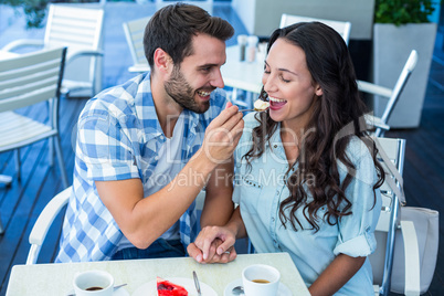 Young happy couple feeding each other with cake