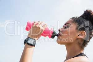 Fit woman wearing smart watch and drinking