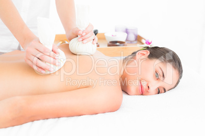 Beautiful brunette enjoying a herbal compress massage