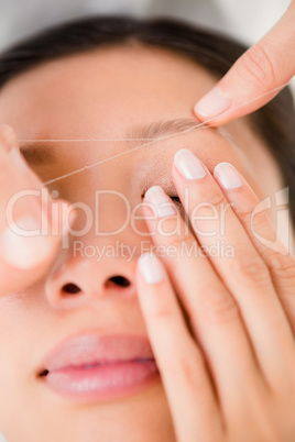 Hands threading beautiful womans eyebrow