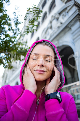 A woman wearing a pink jacket putting her headphones