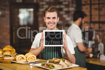 Smiling waiter holding a digital tablet