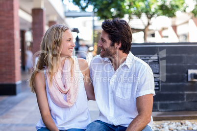 Smiling couple sitting and putting arms around