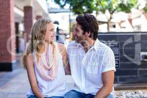 Smiling couple sitting and putting arms around