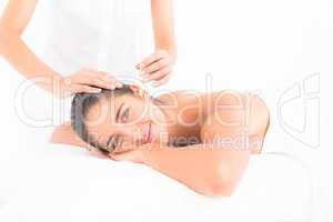 Beautiful woman receiving ear candle treatment at spa center