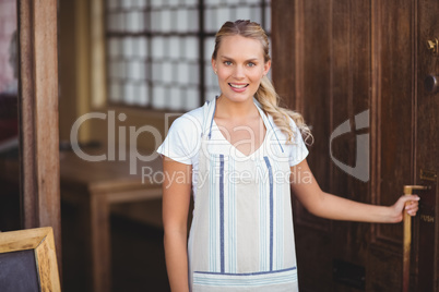 Smiling blonde waitress opening the door