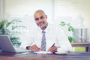 Smiling businessman writing on a notebook