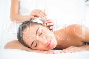 Beautiful woman receiving ear candle treatment at spa center