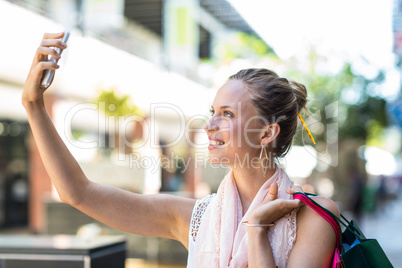 Young woman taking a selfie with her shopping bags