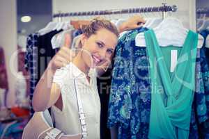 Smiling woman browsing clothes and thumbs up