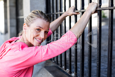 A beautiful woman stretching her body against a fence