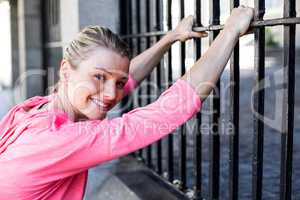 A beautiful woman stretching her body against a fence